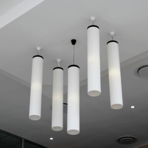 Minimalist modern interior with cylindrical hanging lights on a white ceiling.